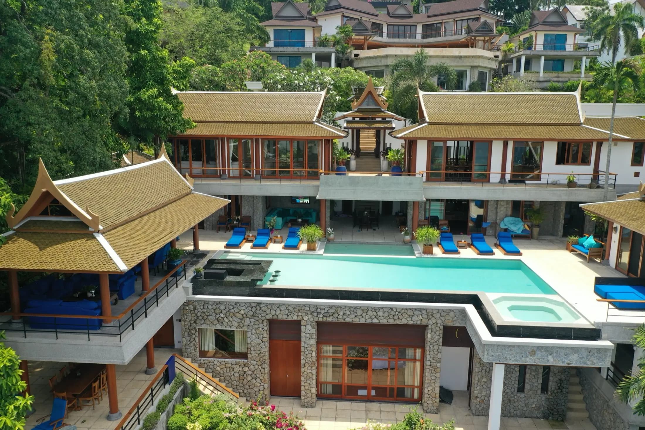 Symmetrical drone view of a hillside Thai villa above its infinity-edge pool and spa