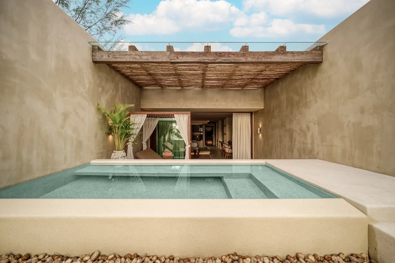Aqua plunge pool framed by warm plaster walls and a timber pergola