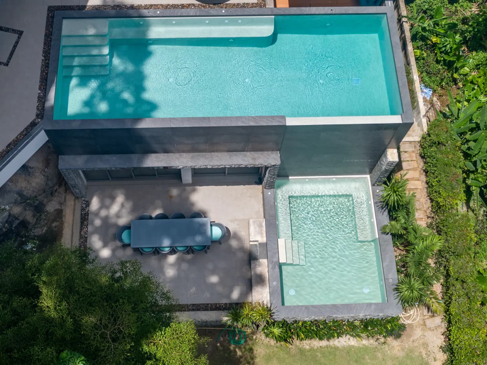 Aerial view of a raised stone-clad pool, spa and garden terrace