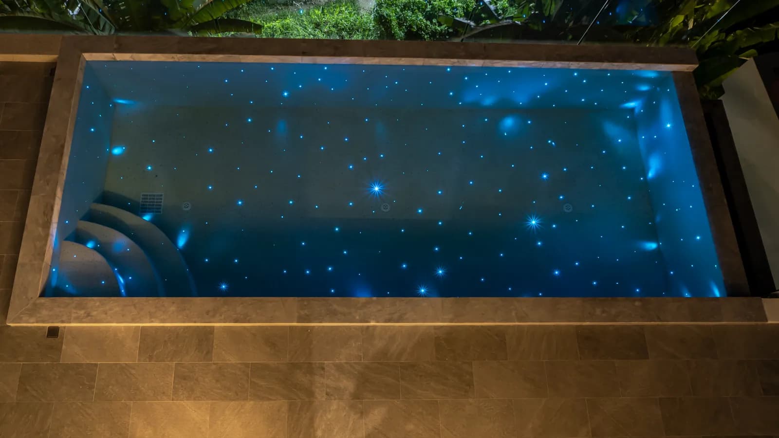 Travertine-framed plunge pool scattered with blue fibre-optic stars