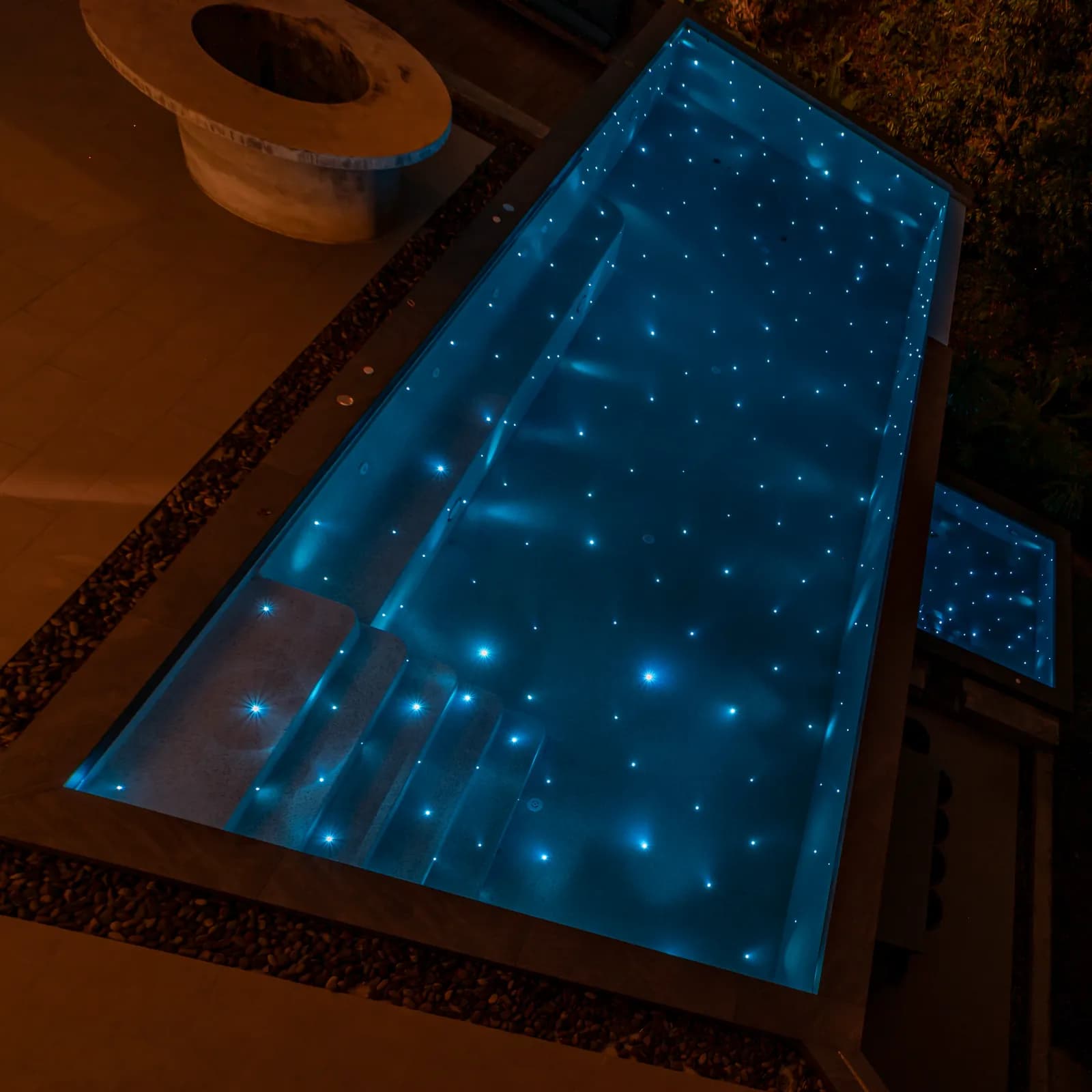 Overhead night view of a lap pool and spa sparkling with starlight points