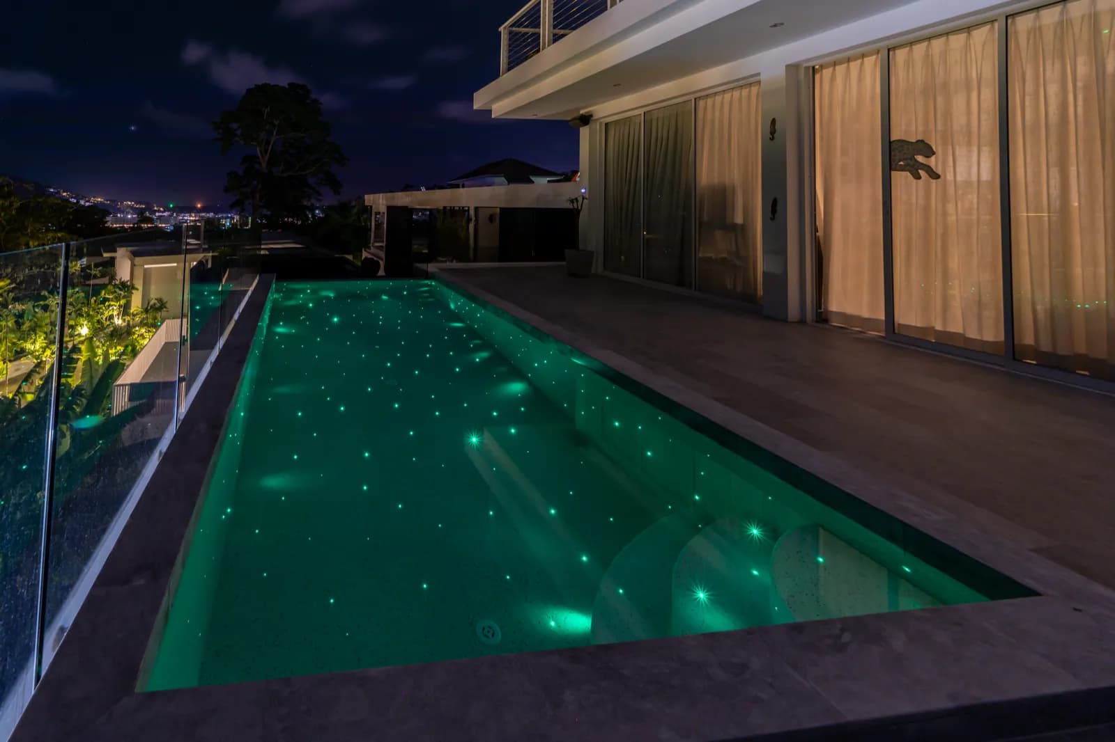 Terrace lap pool glowing emerald green with starlight at night