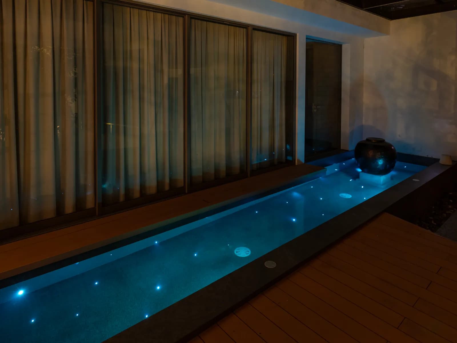 Slim indoor lap pool with starlight points along a timber deck