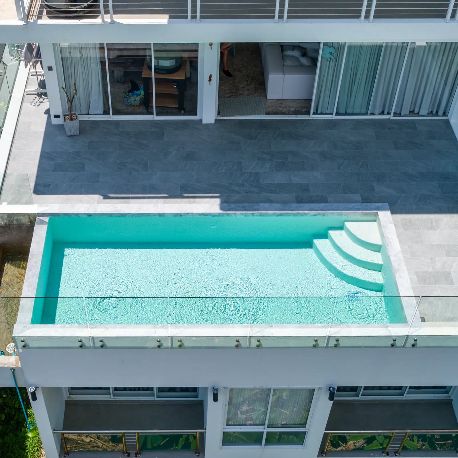 Drone view of a white villa's terrace pool with curved corner steps