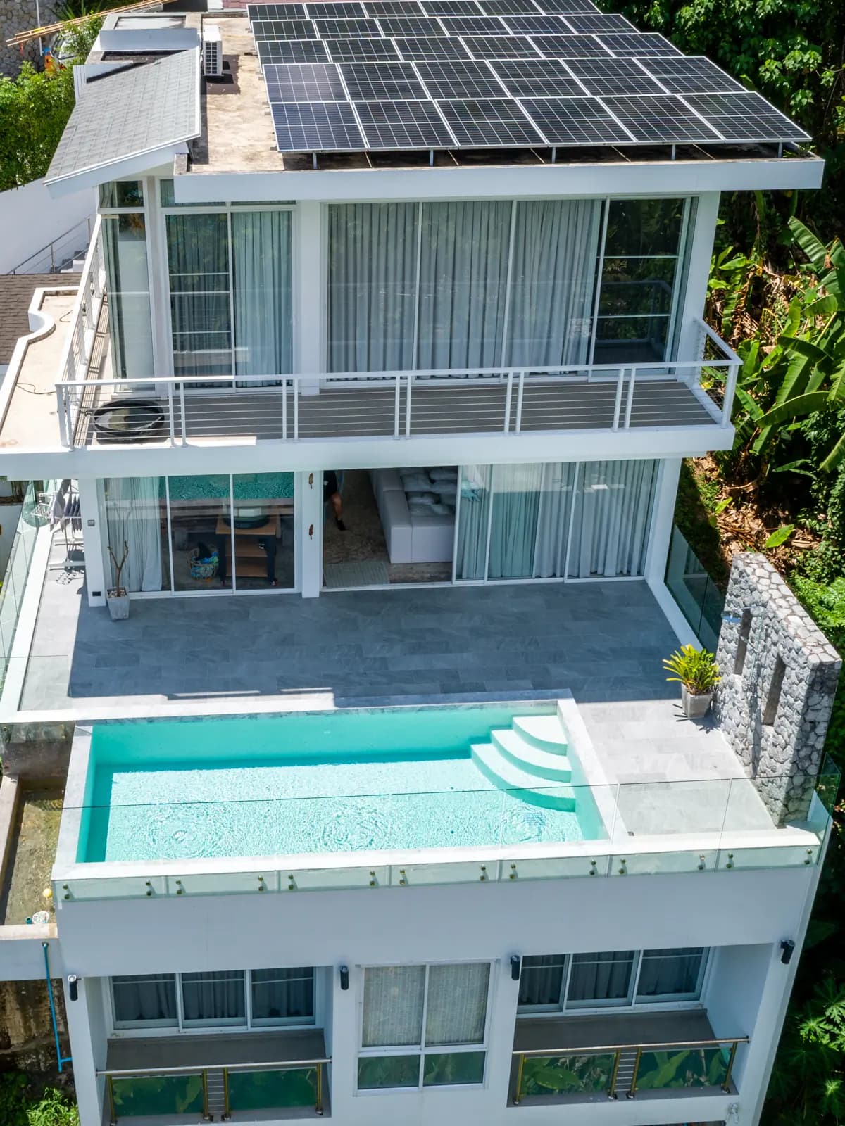 Multi-level white villa with a turquoise terrace pool seen from the air