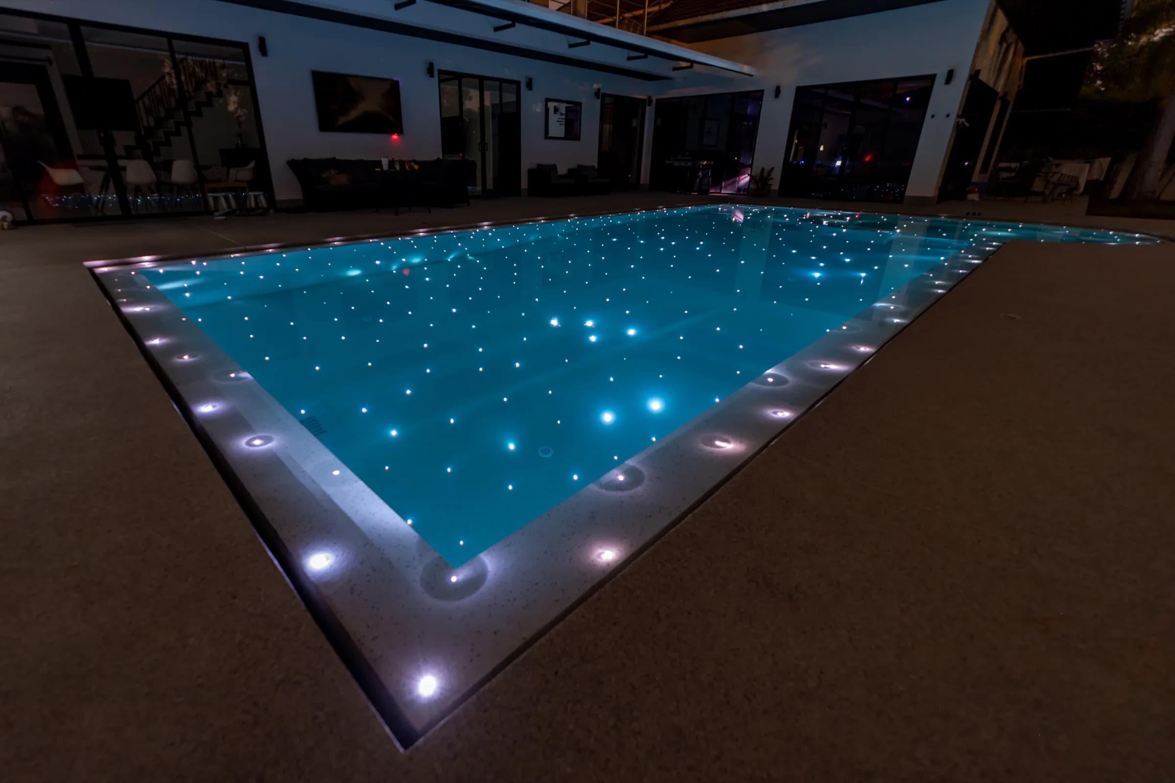 Rectangular pool at night lit by hundreds of fibre-optic stars and edge lights