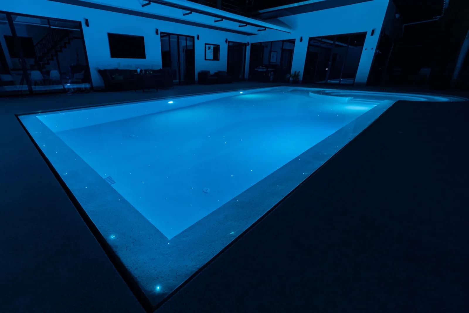 Softly lit rectangular pool glowing pale blue at dusk