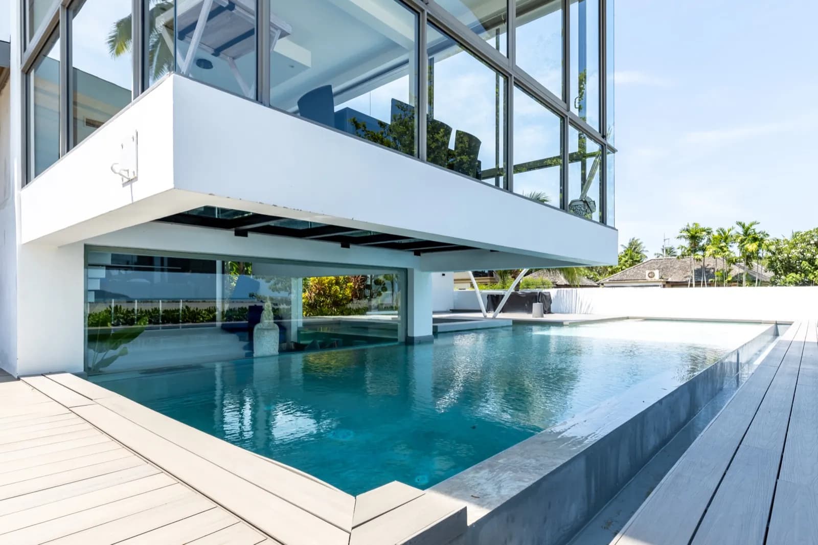 Pool extending beneath a cantilevered glass upper floor