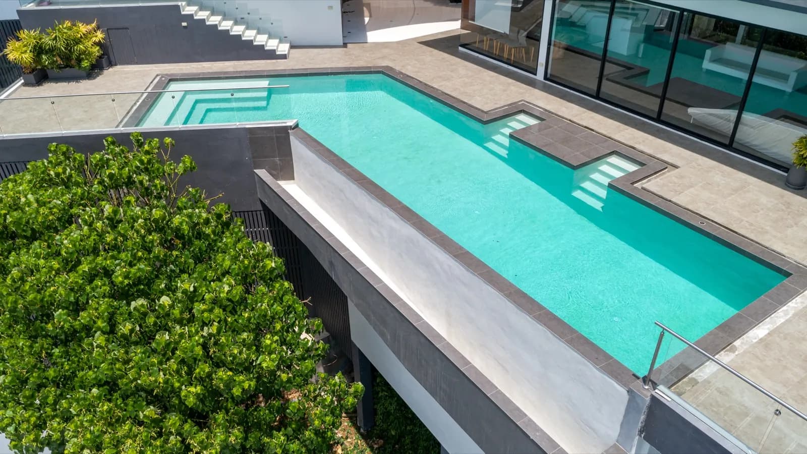 Aerial view of a cantilevered villa pool edge above tropical treetops