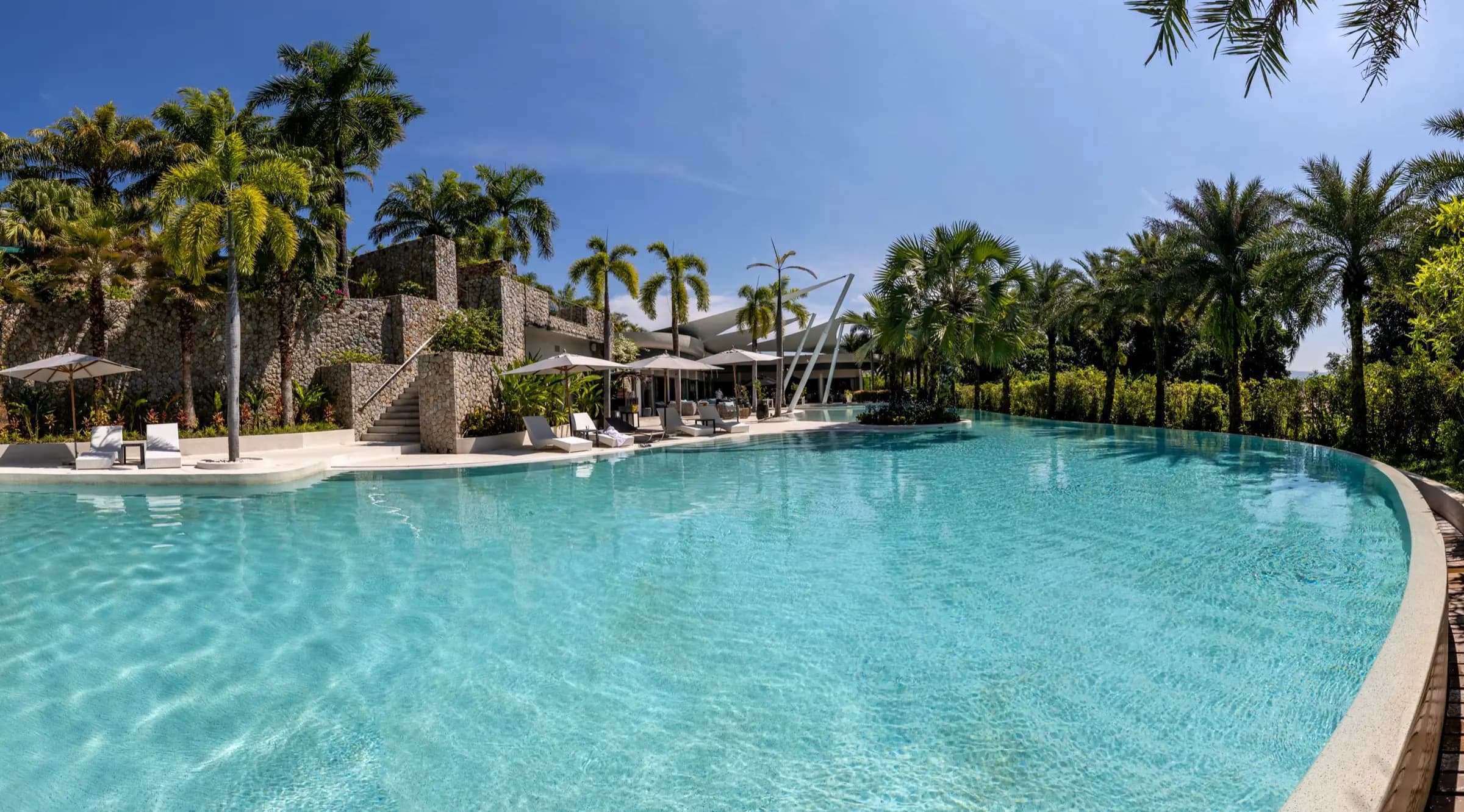 Panorama of a sweeping aqua lagoon pool framed by palms