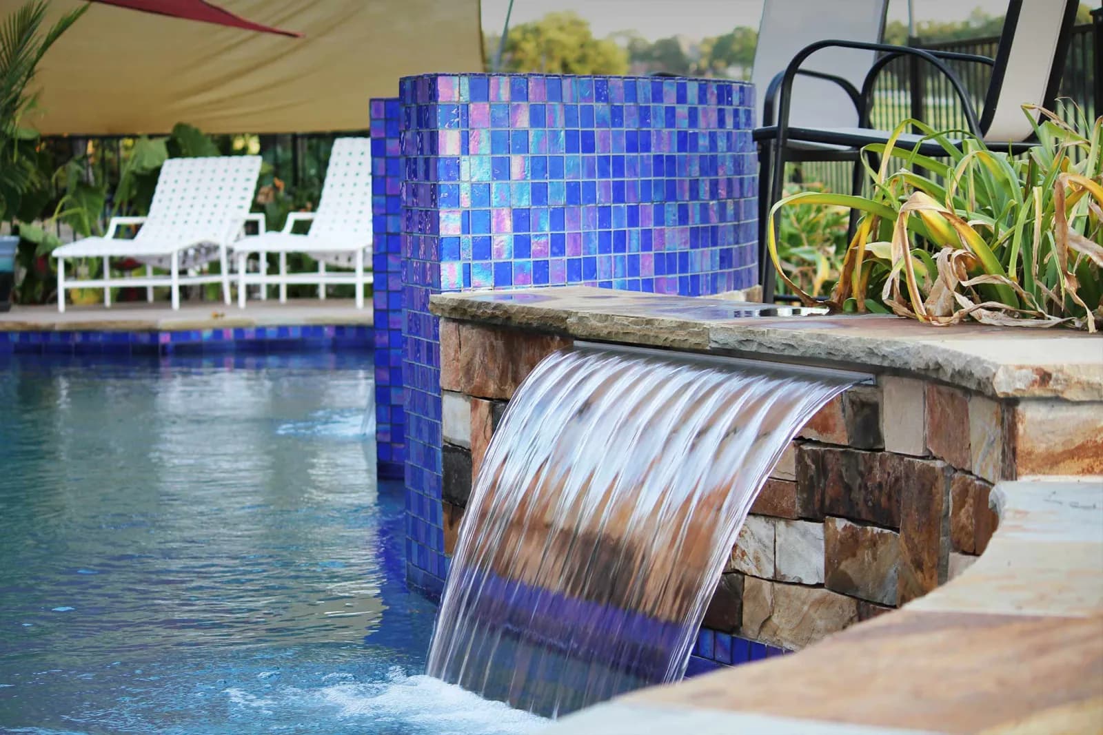 Water sheeting into a pool from a wall of iridescent blue Lightstreams glass tile