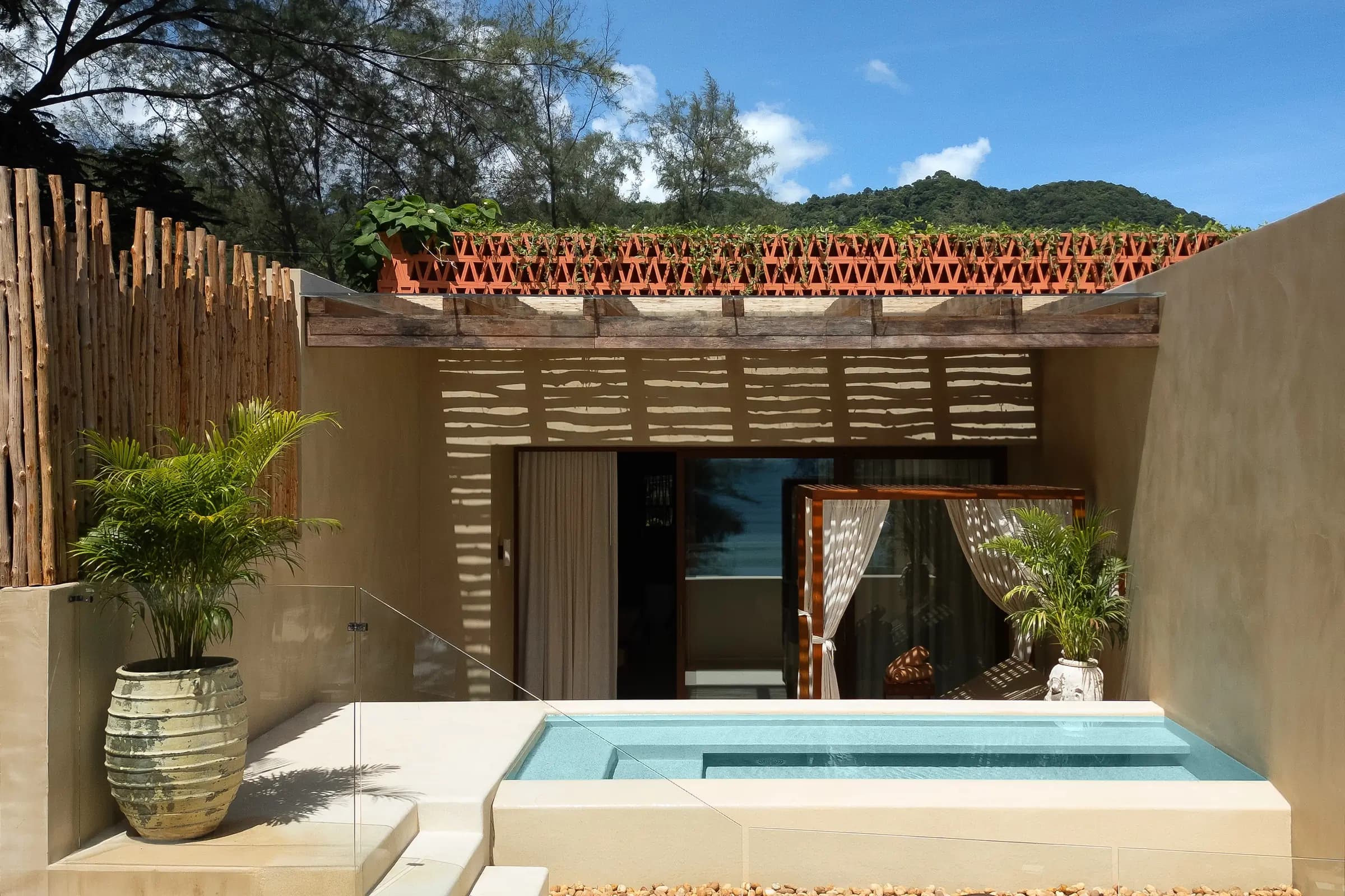 Suite courtyard plunge pool with bamboo screen and green hills under a blue sky