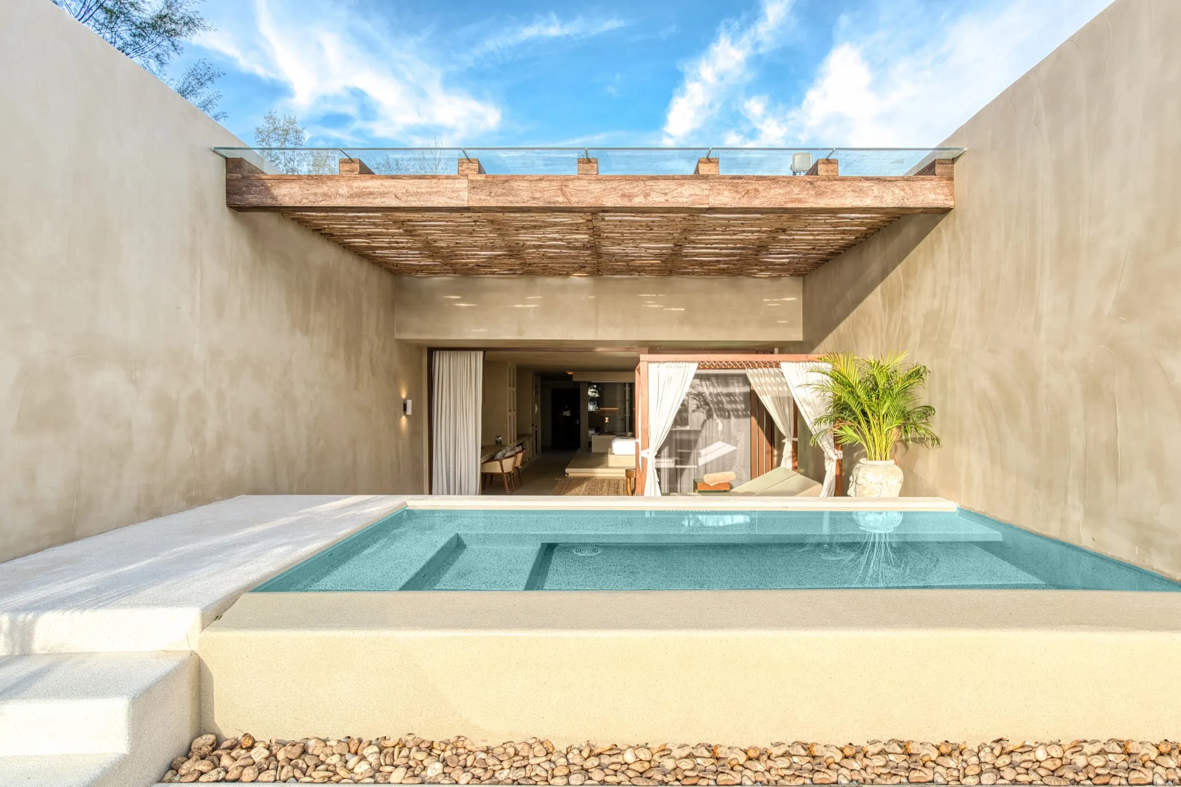 Symmetrical view of a raised aqua plunge pool in a sand-toned open-air courtyard
