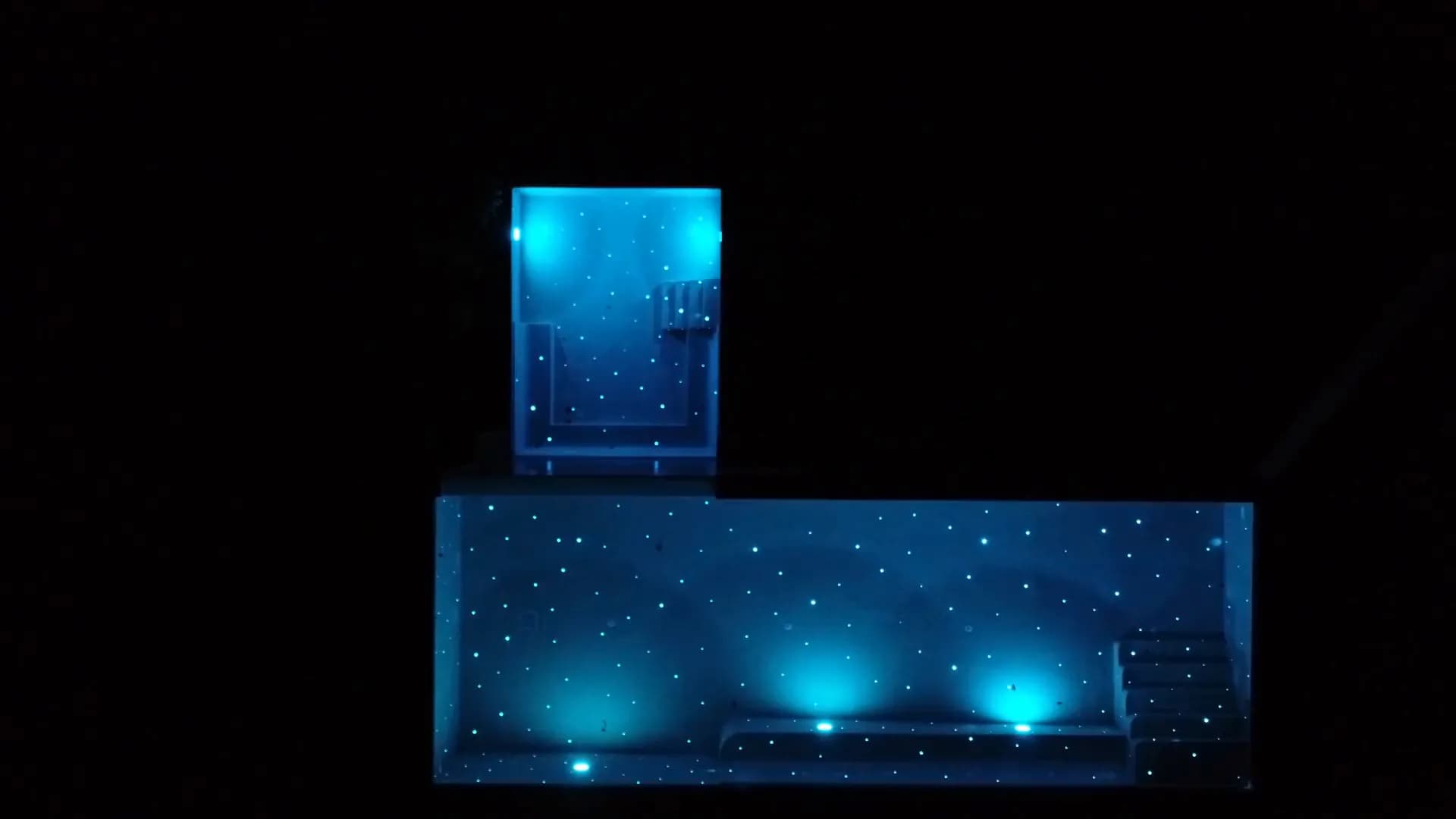 Night aerial of a Kamala pool and spa glowing cyan with fibre-optic starlight