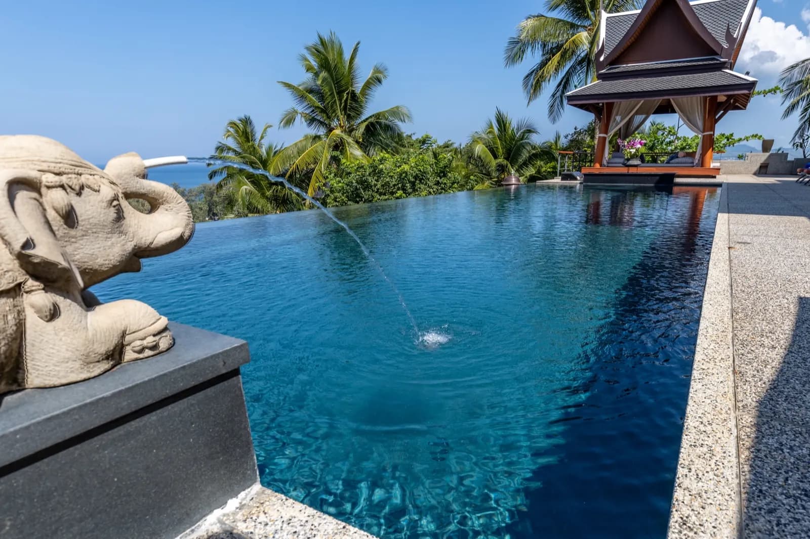 Carved elephant fountain arcing over deep blue-green water
