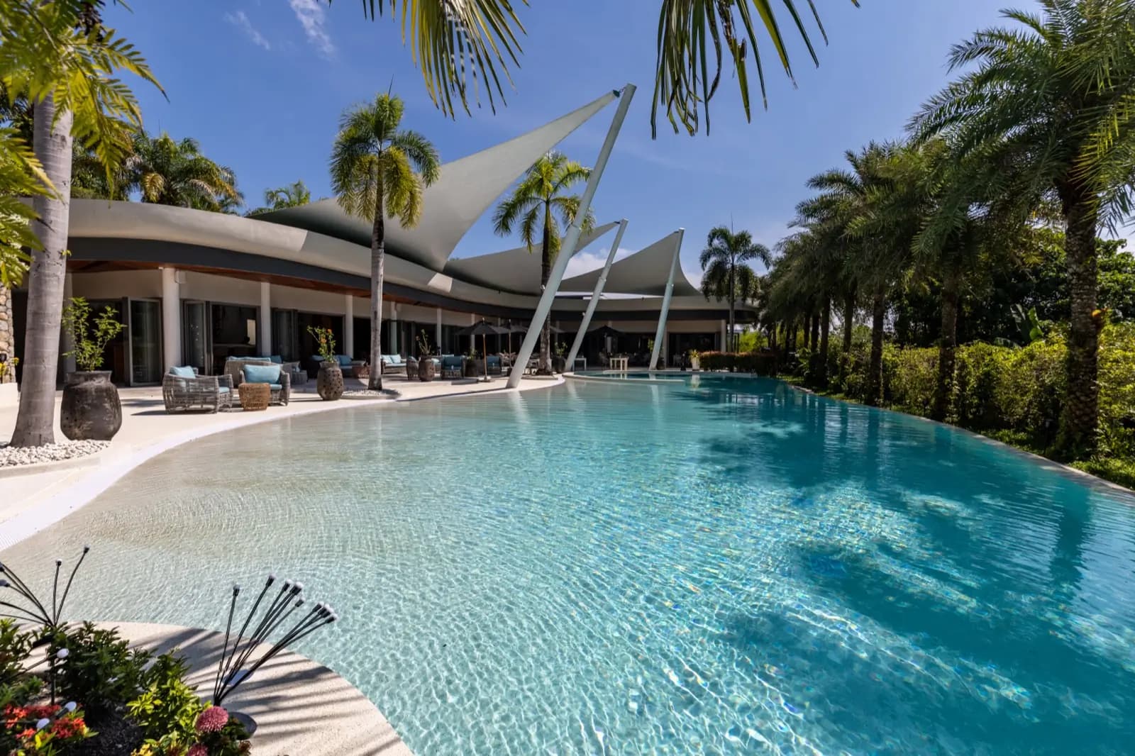 Lagoon pool fronting a clubhouse with sculptural sail-shade canopies